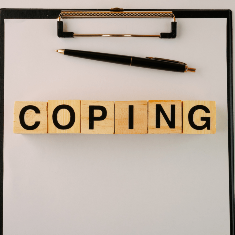 clipboard with scrabble type words spelling coping ont op of paper, pen above