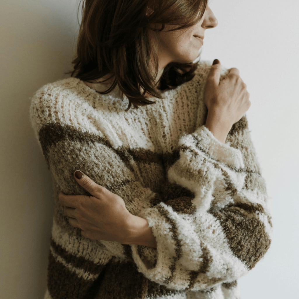 woman looking off to side hugging herself