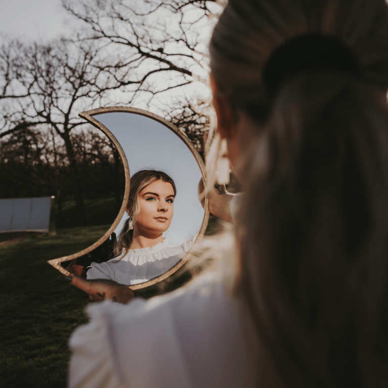woman looking at herself in crescent shaped moon mirror